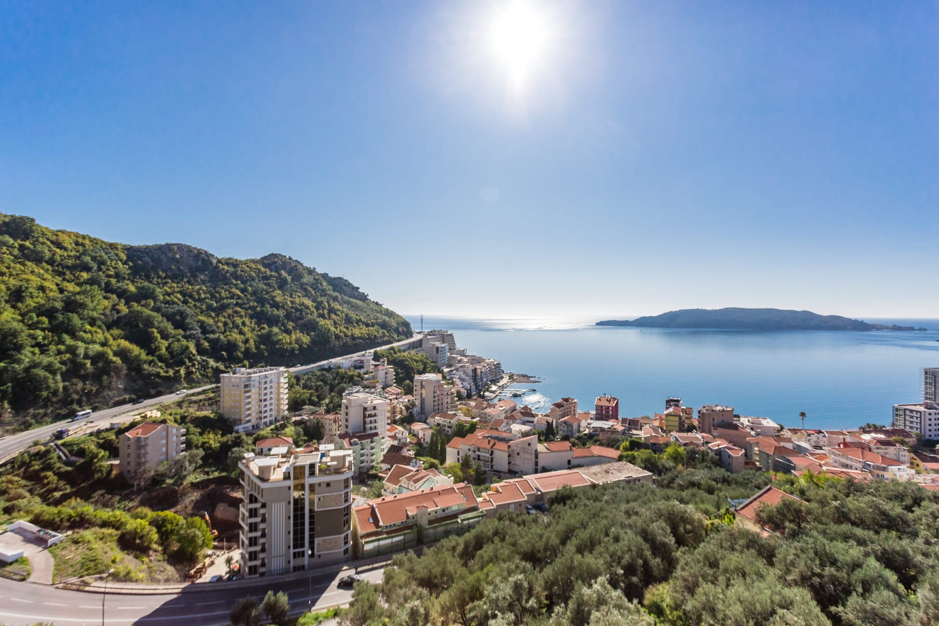 Panoramski pogled na more i letovalište Rafailovići, Budvanska rivijera, Crna Gora: gradska izgradnja i zeleni brežuljci.