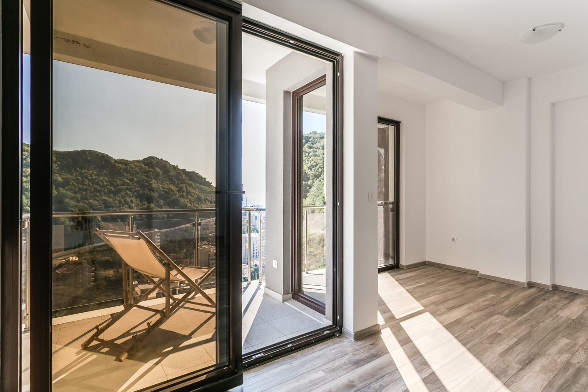Svetla dnevna soba u penthausu u Rafailovićima, Crna Gora, sa izlazom na balkon i panoramskim pogledom na planine i more.