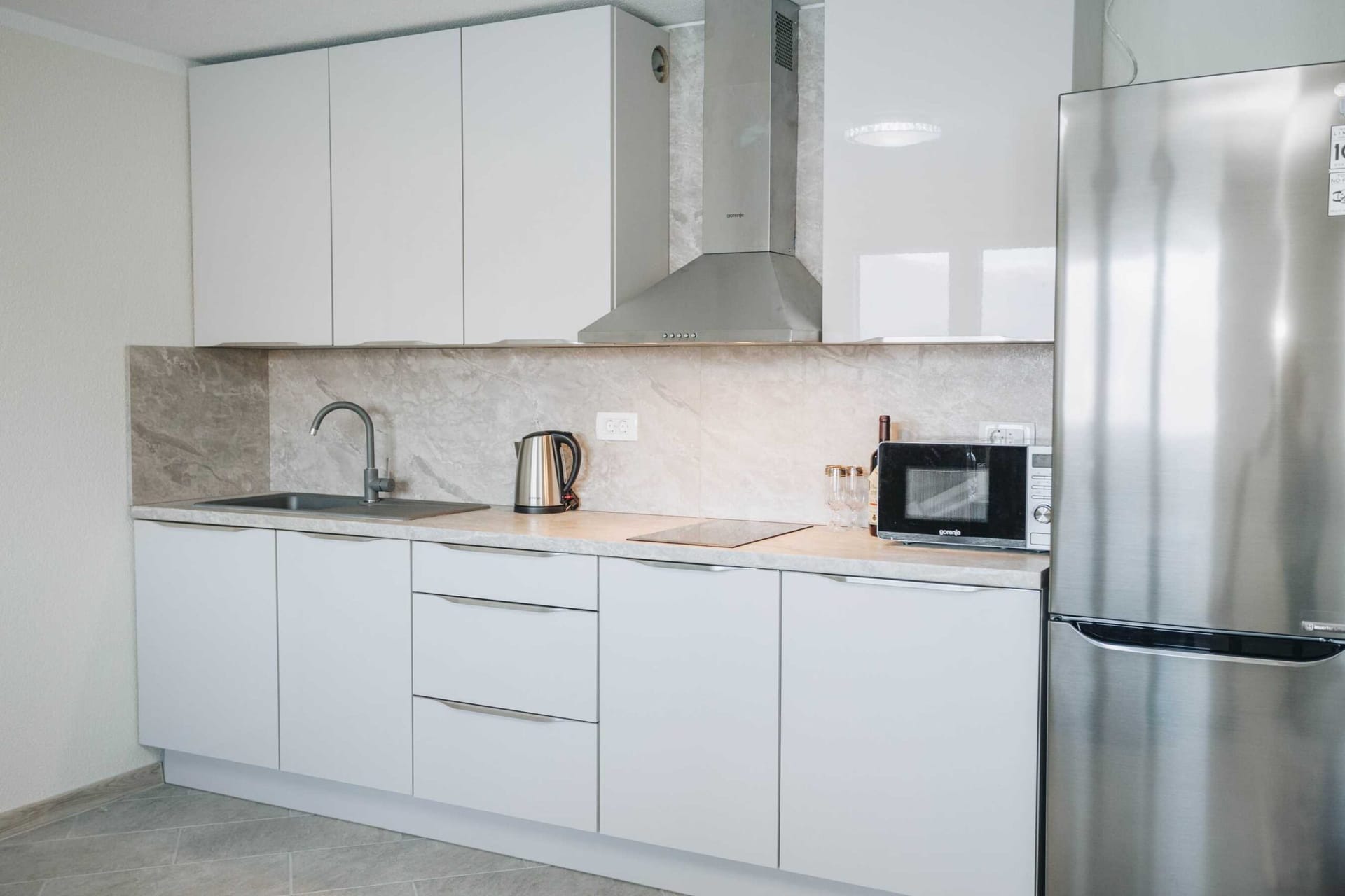Современная белая кухня с техникой Gorenje в апартаментах на вилле в Крашичи, Черногория.