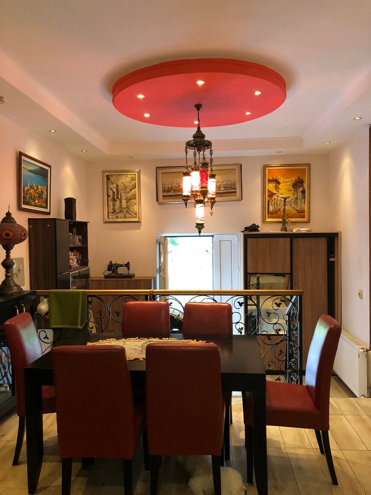 Salon avec coin repas dans un mini-hôtel, Herceg Novi, Monténégro : plafond rouge, lustre vintage et mobilier.