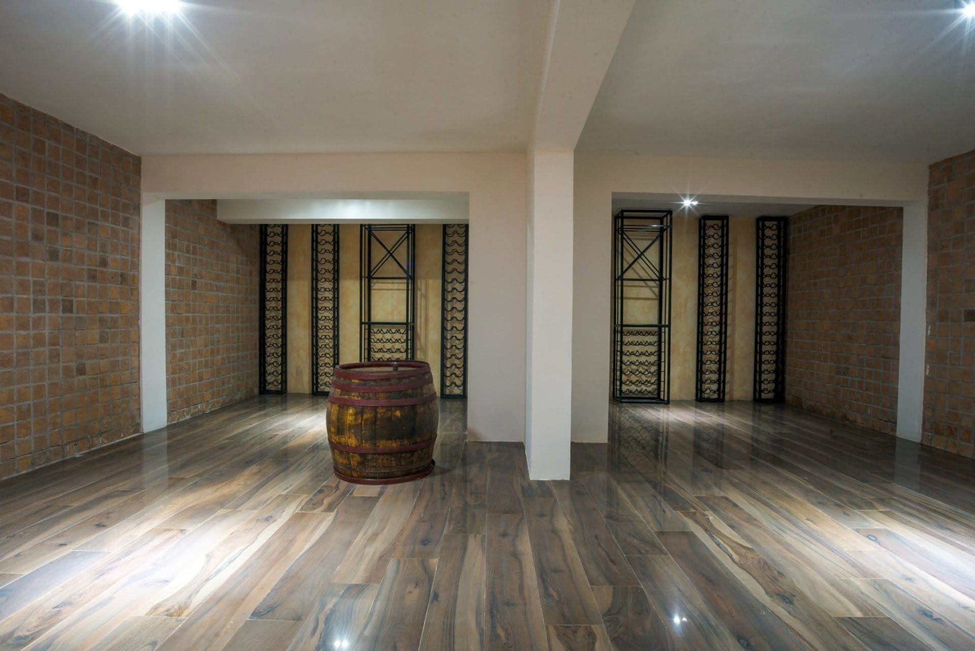 Wine cellar with a wooden barrel and shelving in a luxury villa in Budva, Montenegro, with brick and wood finishes.