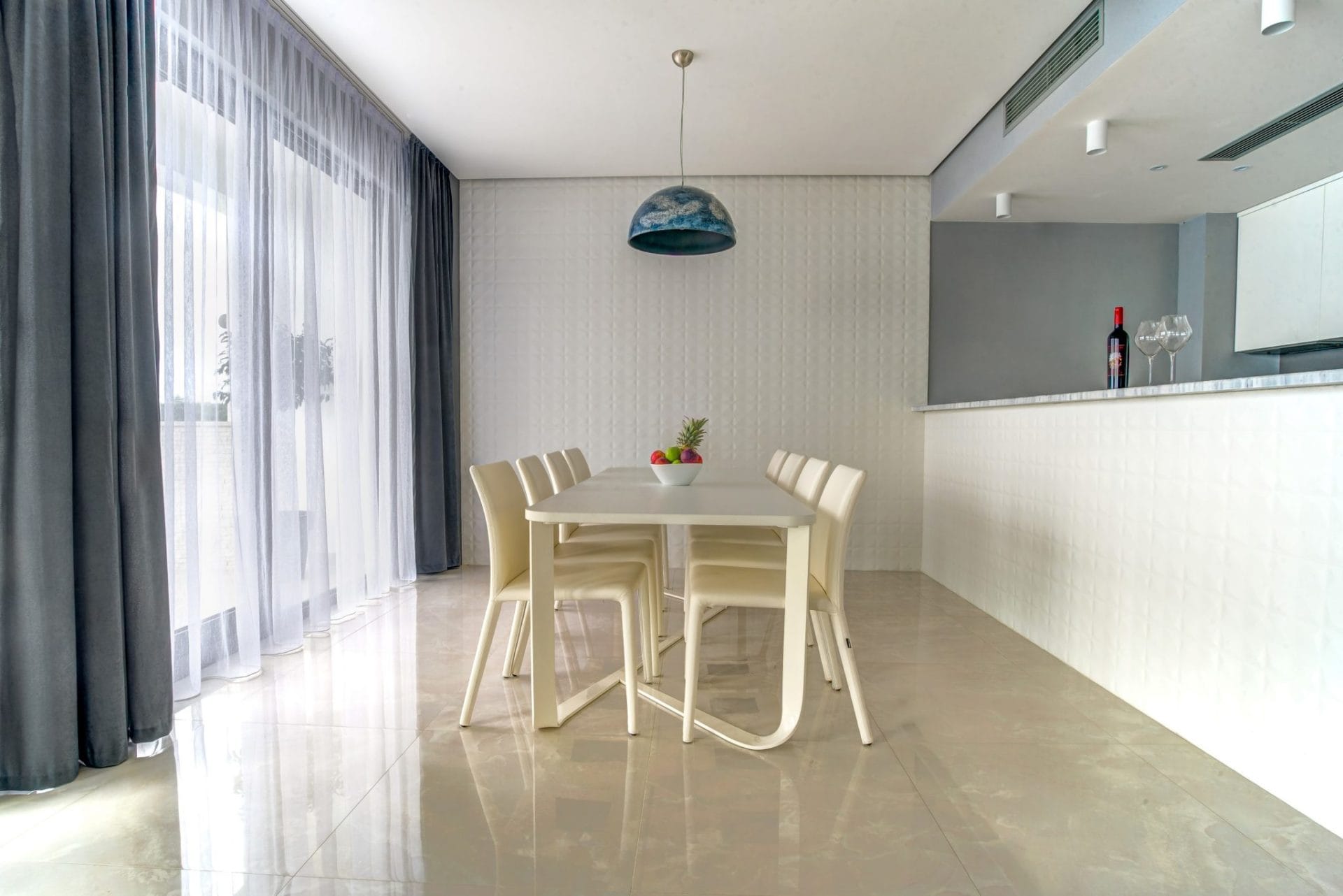Modern dining area with a white table and chairs in a villa interior in Budva, Montenegro. Panoramic windows and decor.
