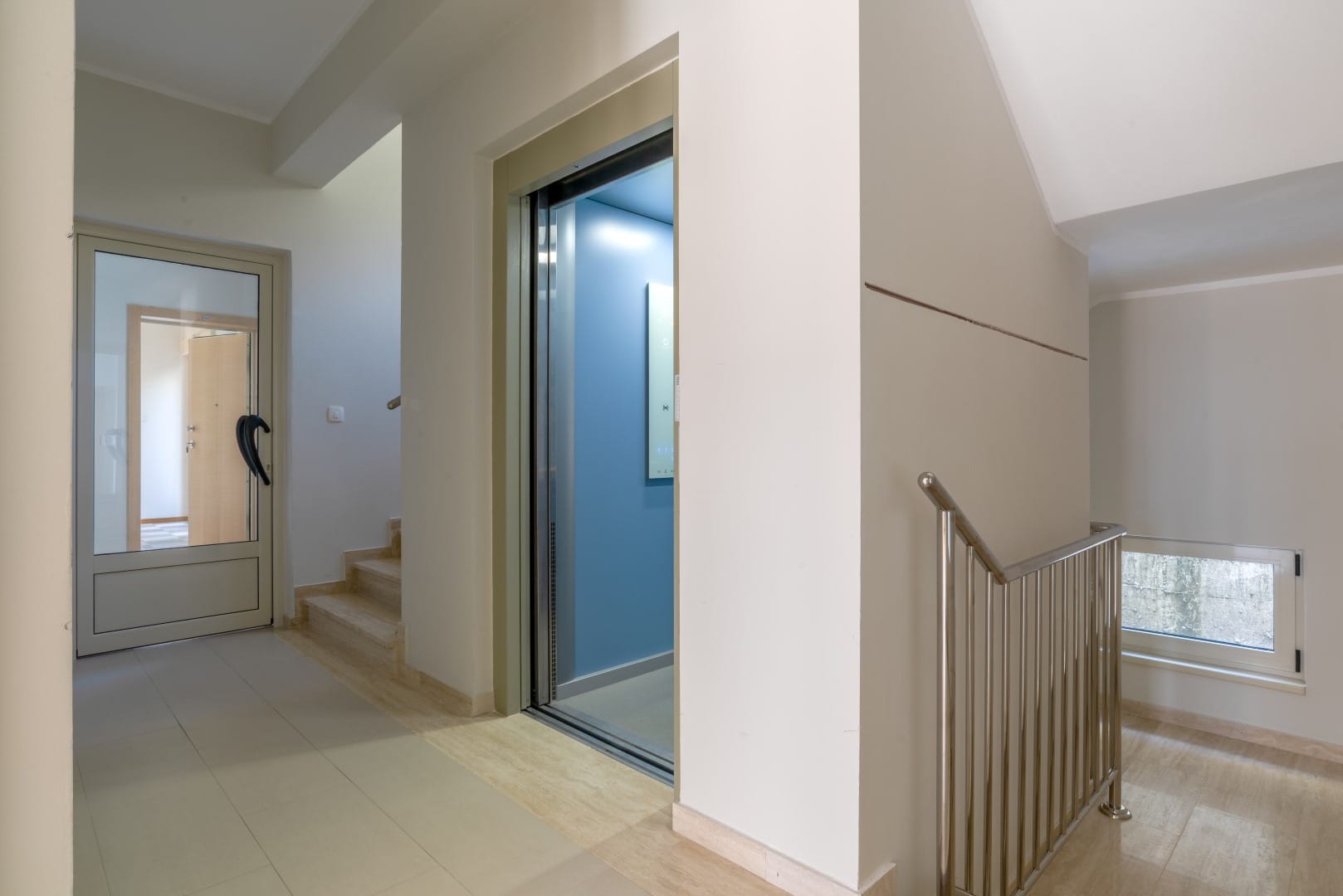 Modern elevator and stair landing with tiled finishes in a residential complex in Orahovac, Montenegro.