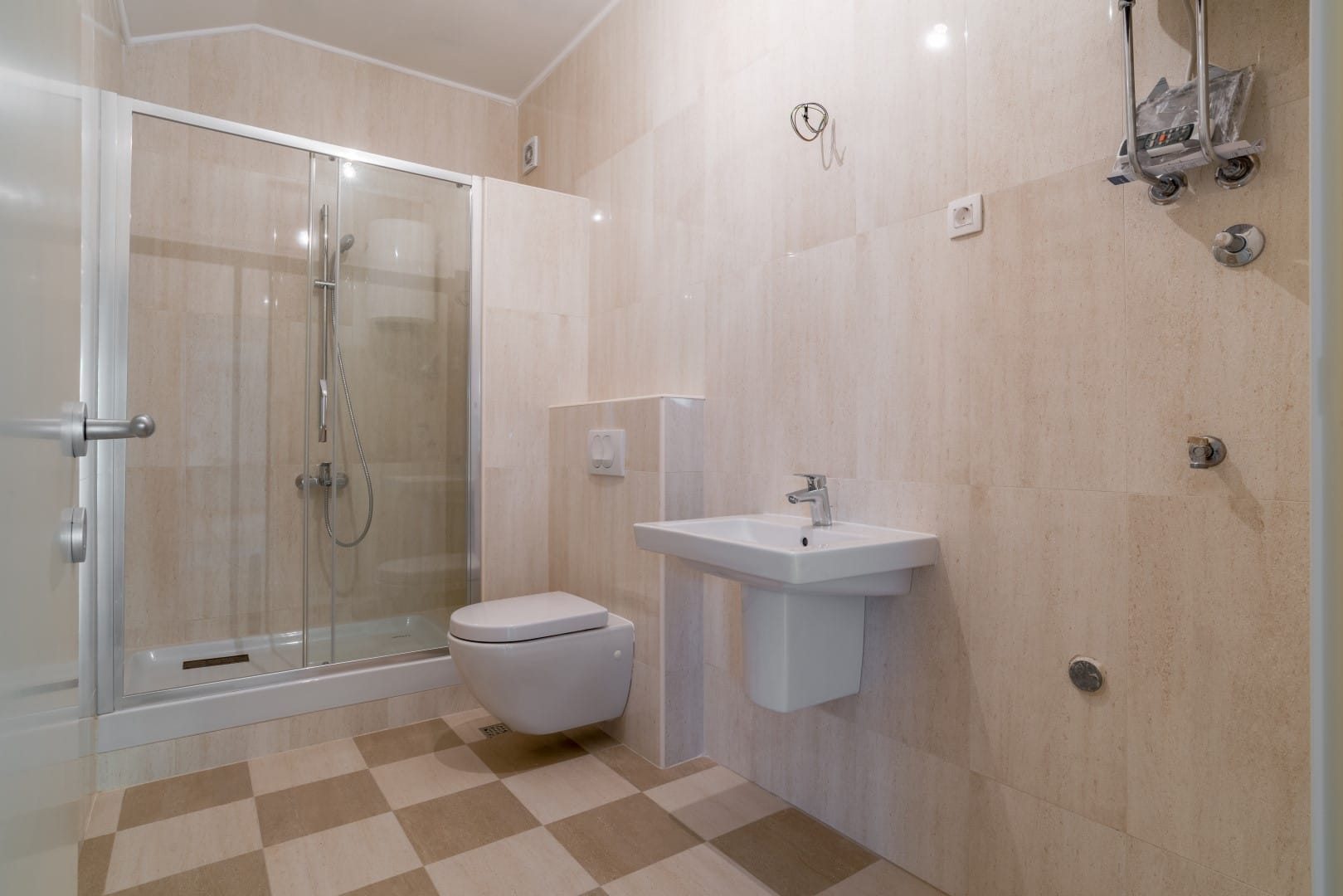 Modern bathroom with a shower cabin in the Orahovac residential complex, Bay of Kotor, Montenegro: beige tiles and fixtures