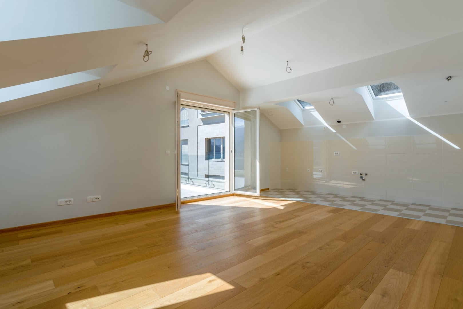 Bright attic living room with parquet flooring and access to a terrace in a residential complex, Orahovac, Montenegro.