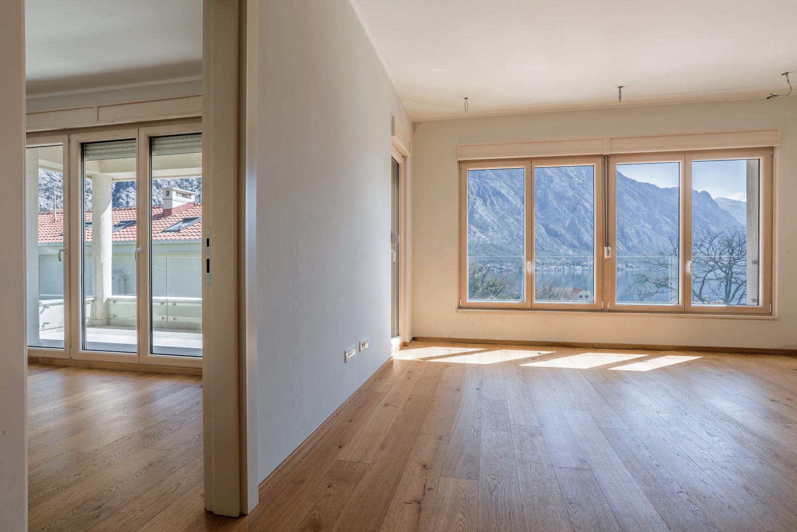 Bright living room with parquet flooring and panoramic views of the mountains and sea in Orahovac residential complex, Bay of Kotor, Montenegro.