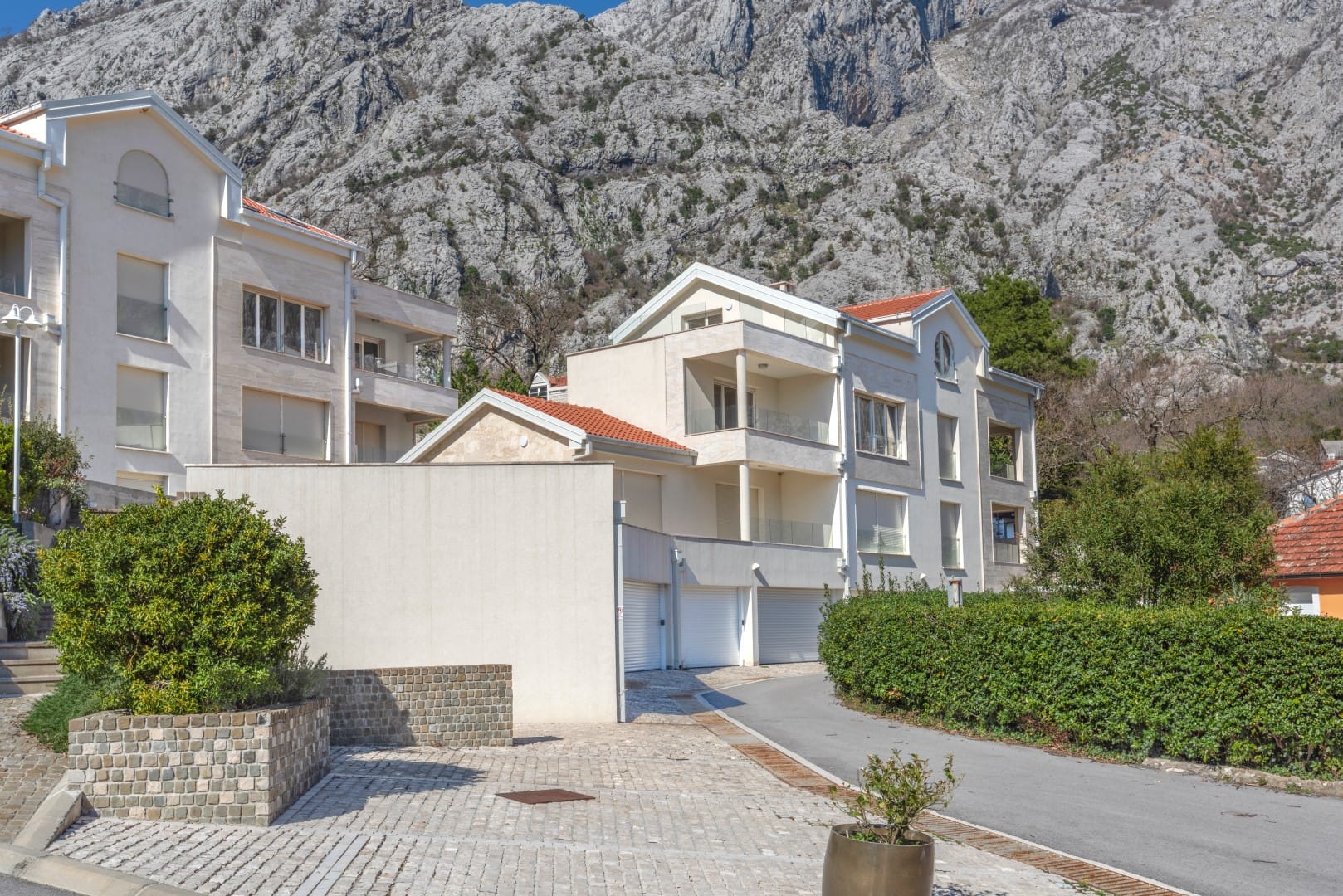 Modern residential complex in Orahovac, Montenegro: light facades, garages, and views of the mountains of the Bay of Kotor.