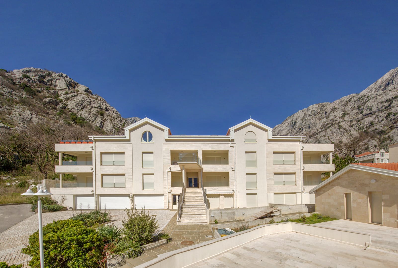 Modern residential complex in Orahovac, Montenegro: building facade with terraces against the backdrop of the mountains of the Bay of Kotor.