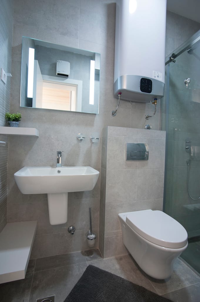 Savremeno kupatilo u apartmanu, Budva, Crna Gora: tuš kabina, viseća WC šolja i bojler.