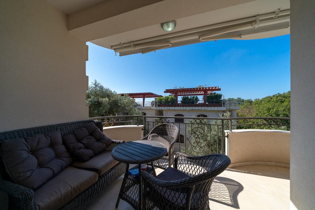 Cozy balcony with wicker furniture and a view of greenery in an apartment in Petrovac, Montenegro.