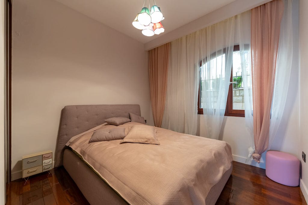 Cozy bedroom with a double bed and an arched window in an apartment for sale, Petrovac, Montenegro.