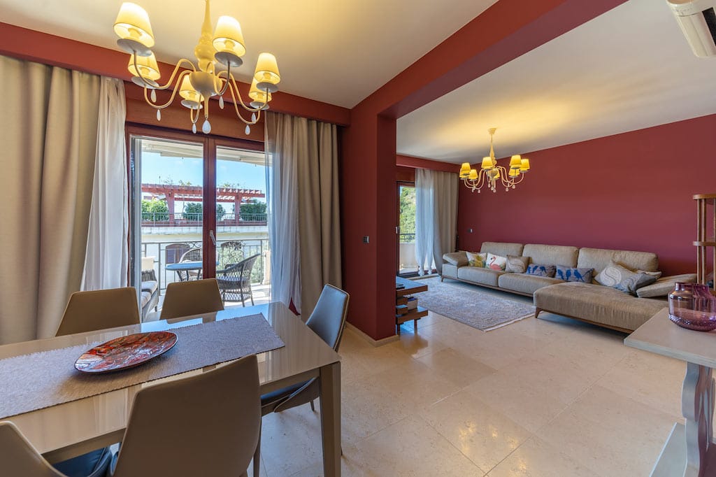 Living room with dining area in an apartment in Petrovac, Montenegro: light furniture, terrace, and red accent walls.