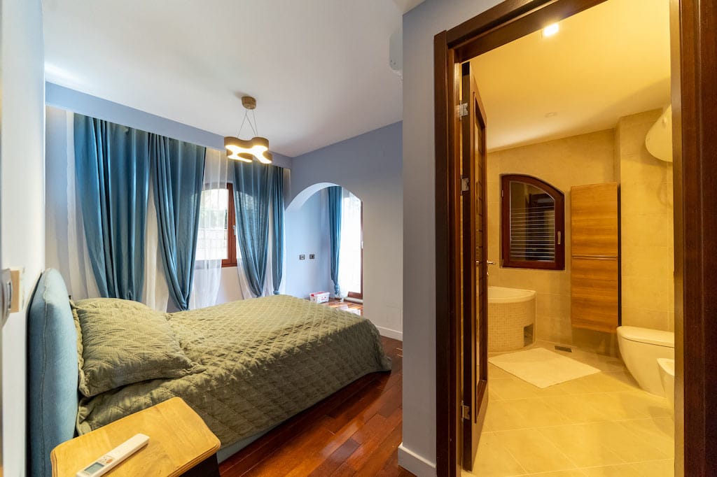 Bedroom with a double bed and bathroom in an apartment in Petrovac, Montenegro: modern interior, parquet flooring.