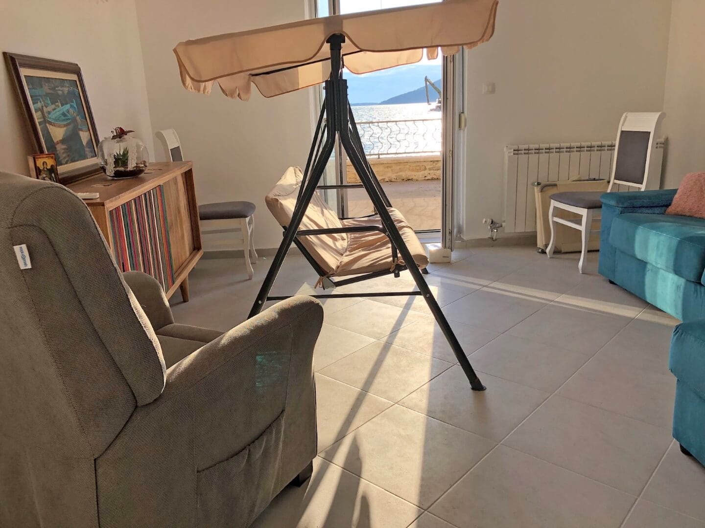 Wohnzimmer mit Schaukel und Meerblick in einer Wohnung in Herceg Novi, Montenegro: helles Interieur, weiche Möbel und Terrasse.
