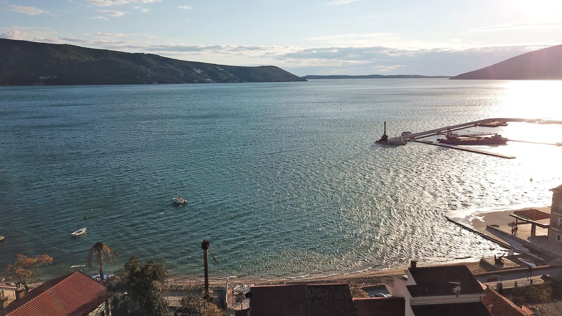 Panoramablick auf das Meer und die Bucht von Kotor von der Wohnung in Herceg Novi, Montenegro: Strand, Anlegesteg und Berge.