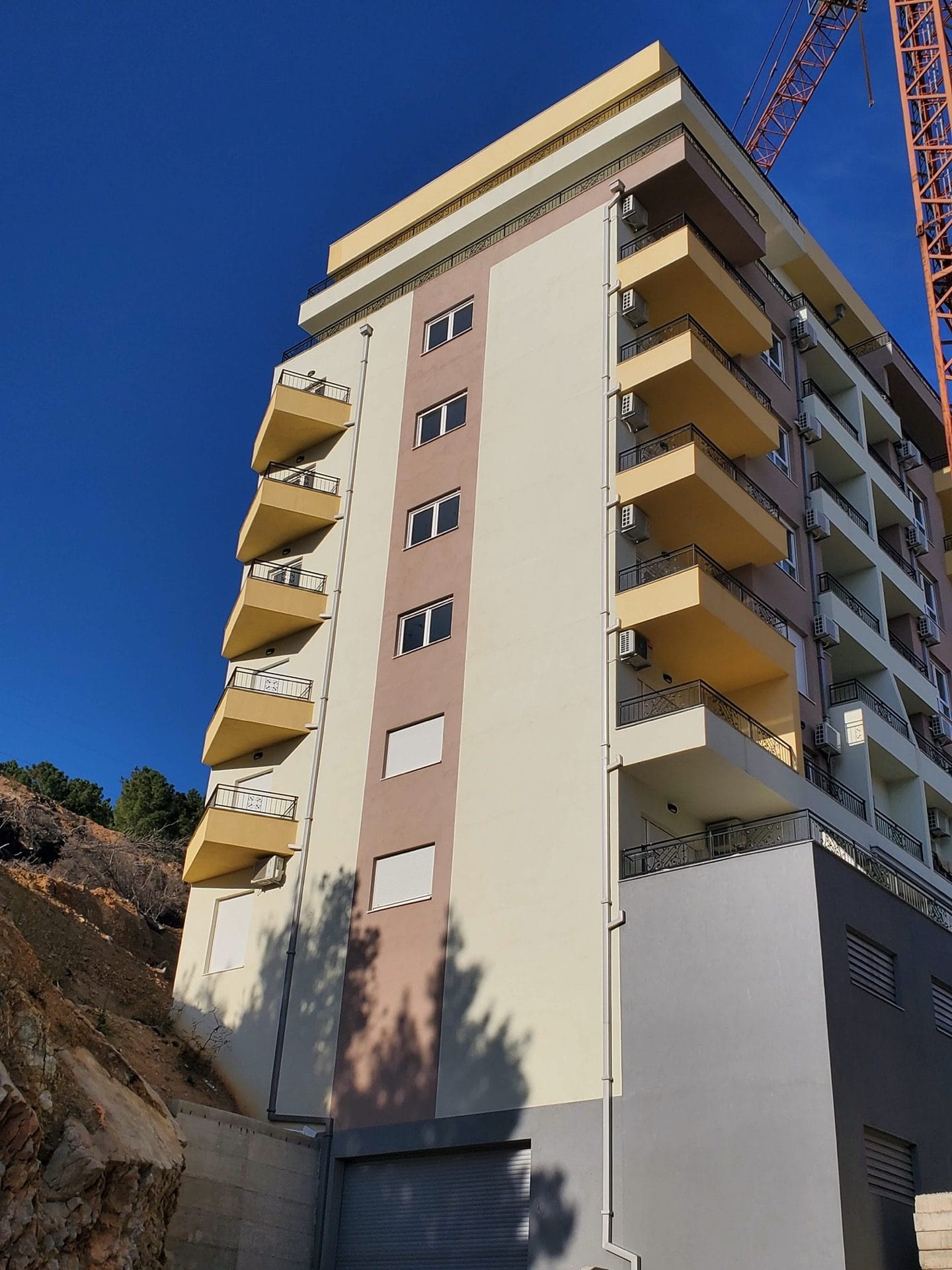 Modern multi-story residential complex with balconies in Budva, Montenegro, exterior view of the building facade.