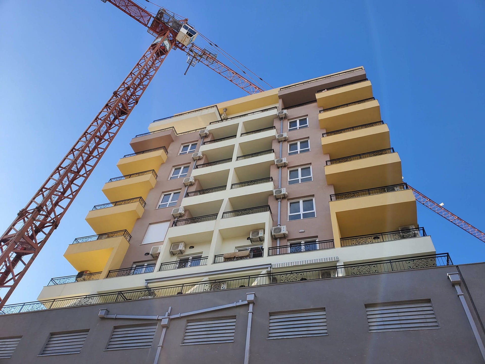 Residential complex under construction in Budva, Montenegro: a modern building with balconies and a construction crane against the sky.