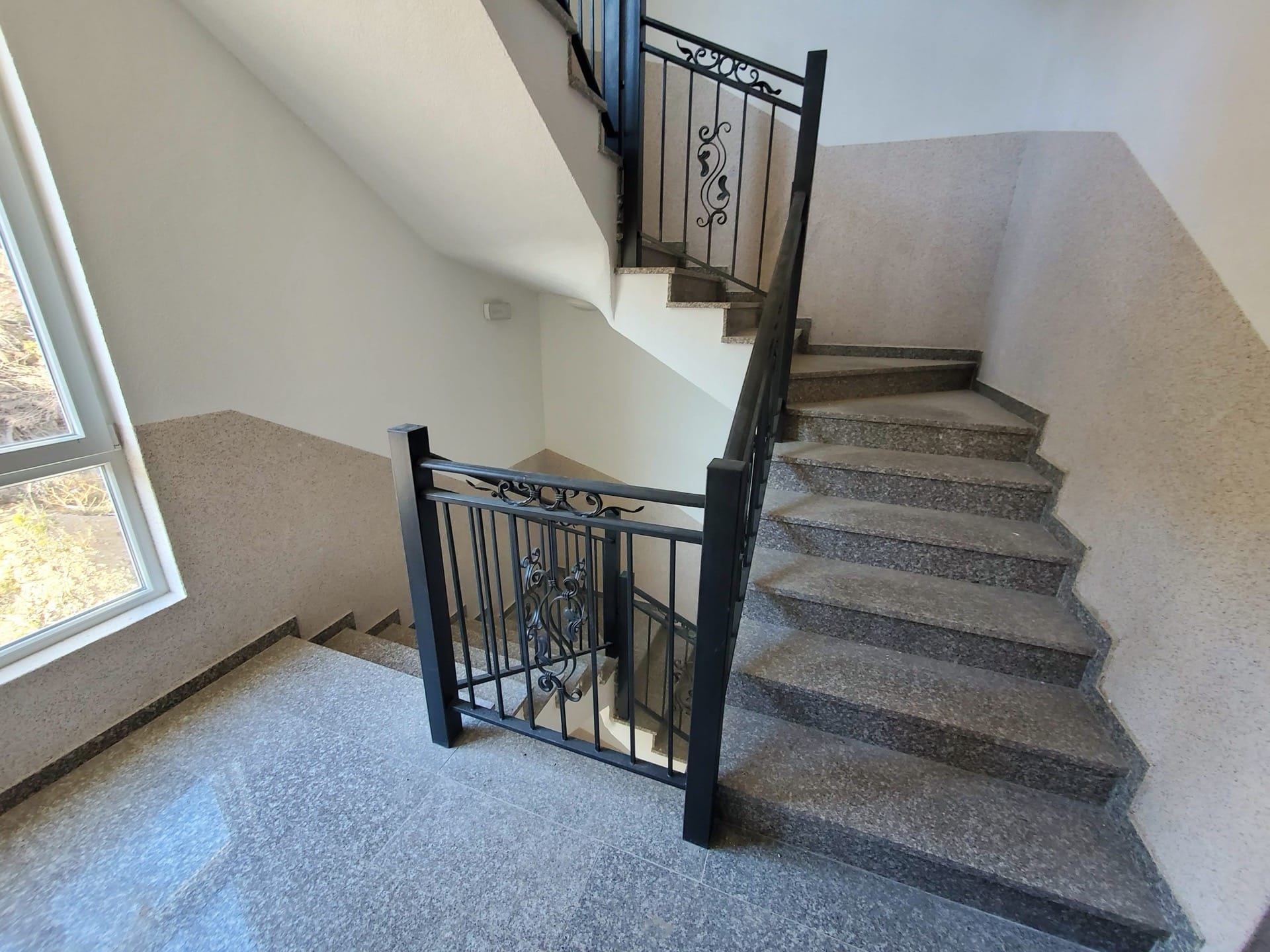 Staircase landing with wrought-iron railings and stone finishes in a residential complex in Budva, Montenegro