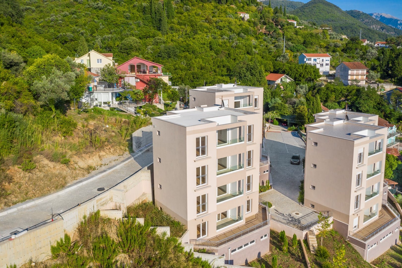Savremene stambene zgrade sa balkonima u okruženju planina i zelenila, Tivat, Crna Gora, pogled na kompleks iz ptičje perspektive