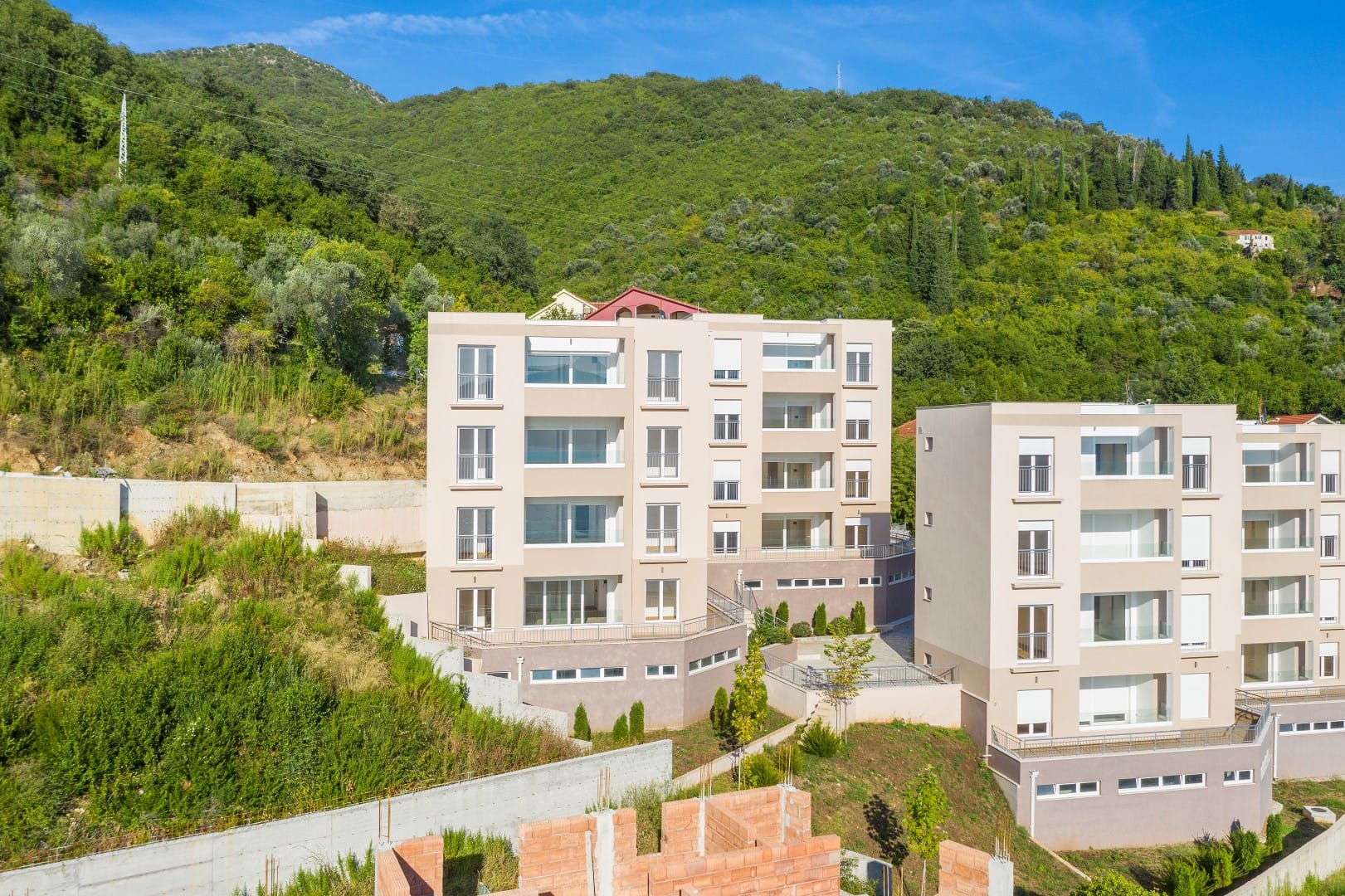 Savremeni stambeni kompleks sa panoramskim prozorima u okruženju planina u gradu Tivat, Crna Gora.