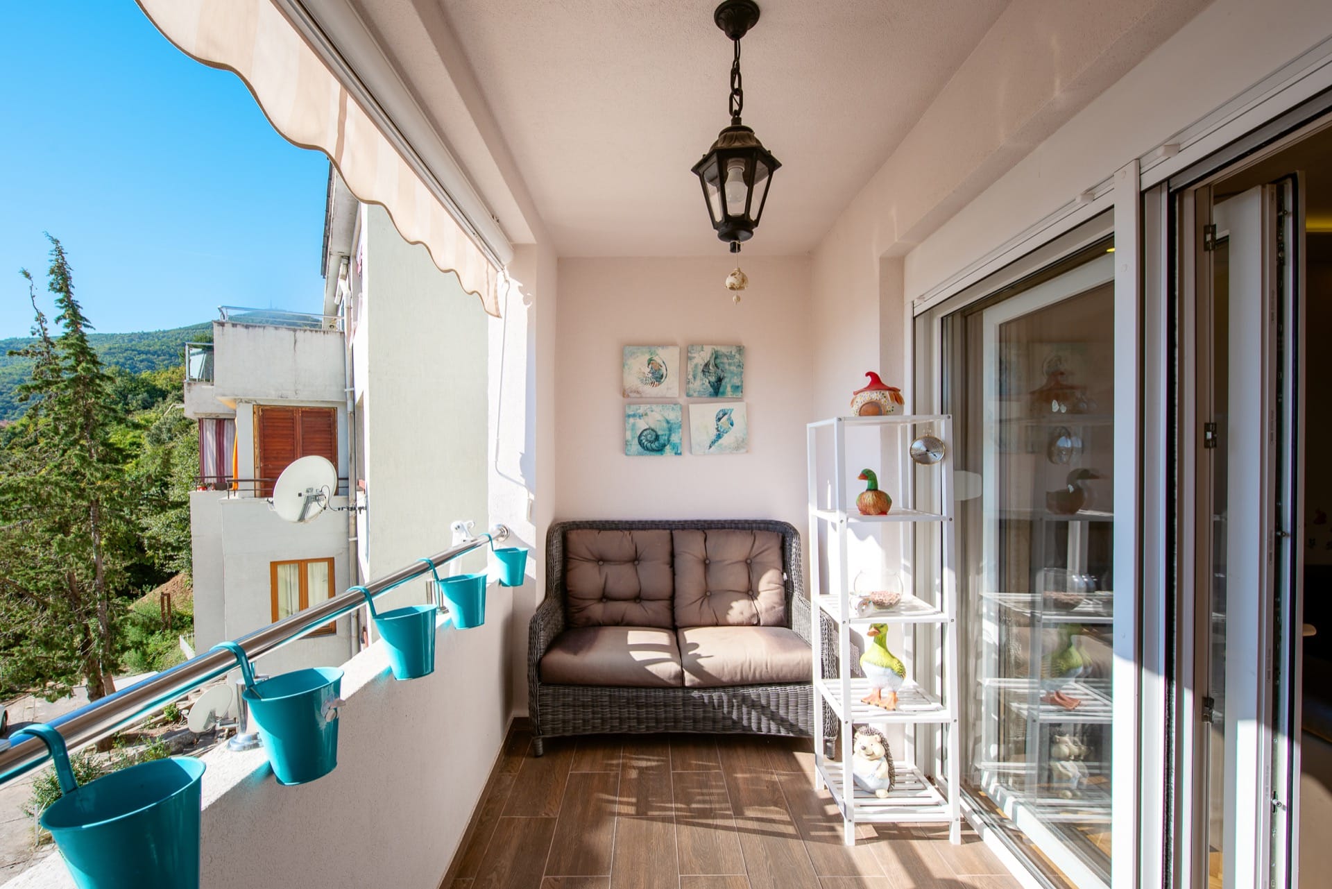 Ugodan balkon s pletenim nameštajem i pogledom na planine u stanu, Budva, Crna Gora.