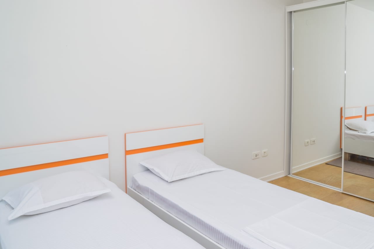 Svetla spavaća soba sa dva singl kreveta i garderoberom sa kliznim ogledalnim vratima u stanu, grad Budva, Crna Gora.
