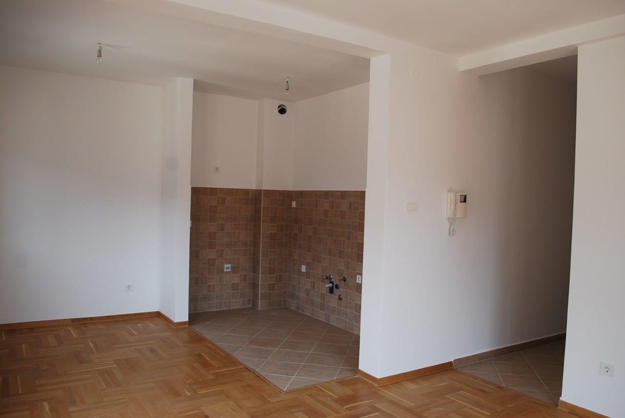 Kuhinja u stanu u Risanu, Crna Gora: svetla obrada, pločasti backsplash, parketni pod, priprema za kuhinjski nameštaj.