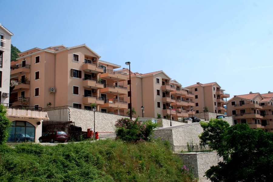 Stambeni kompleks sa bež fasadama i terasama u Risnu, Crna Gora: pogled na višespratnice na brdu.