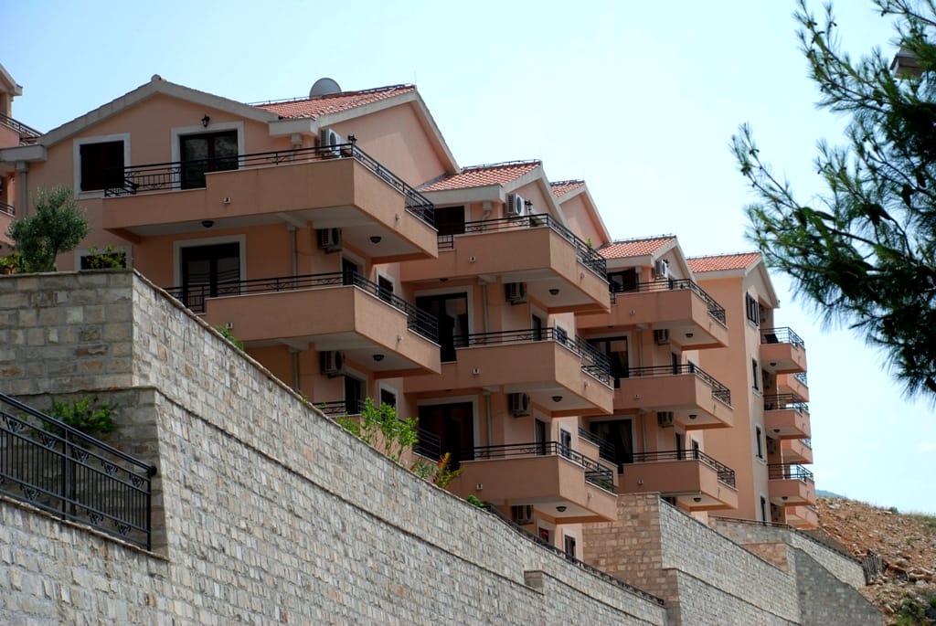 Savremeni stambeni kompleks sa terasama u gradu Risan, Crna Gora: pogled na fasadu zgrade sa kamenim potpornim zidom.