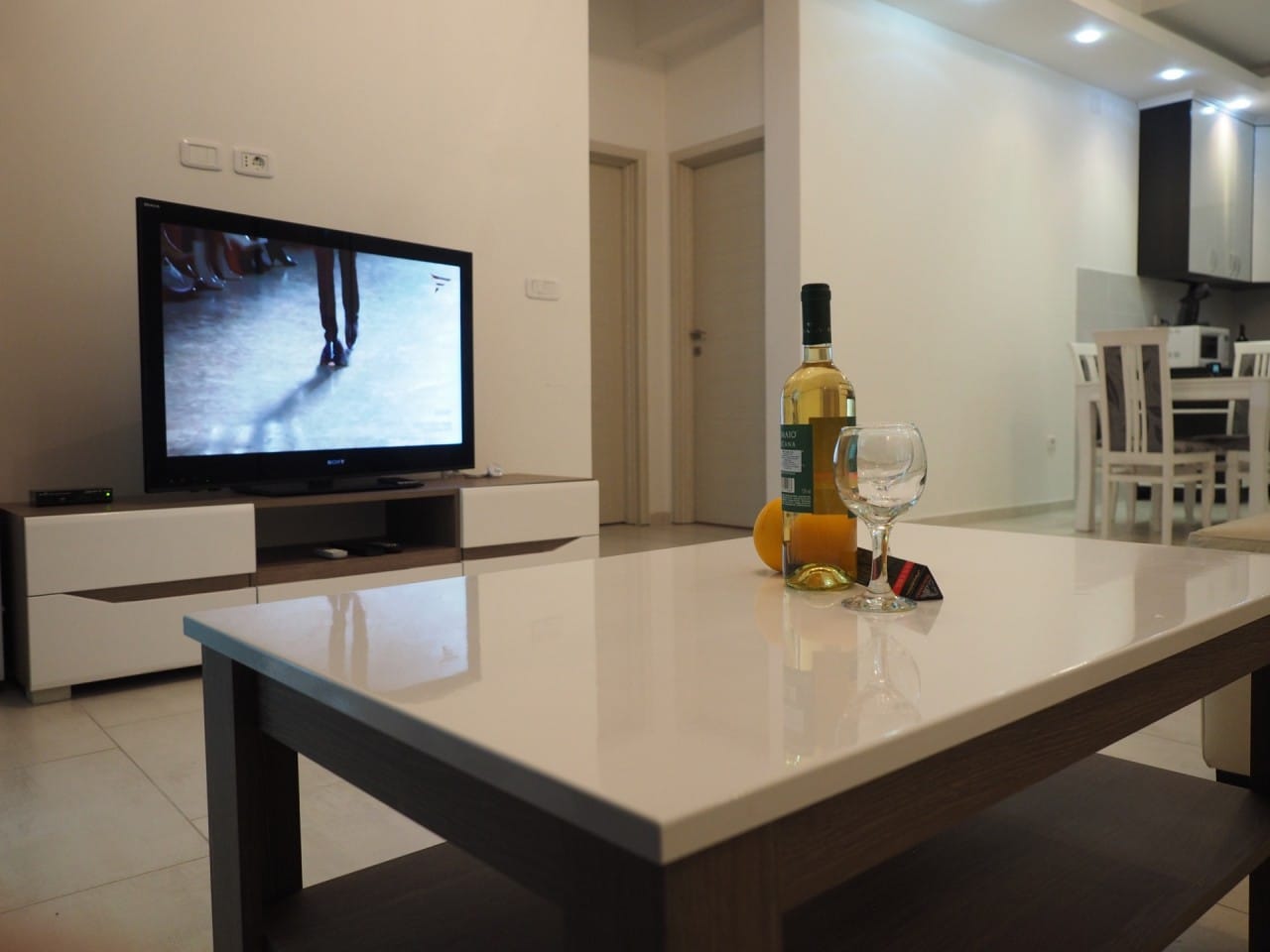 Savremena dnevna soba u stanu u Pržnu, Crna Gora: sjajni klub sto, TV zona i trpezarijski deo.