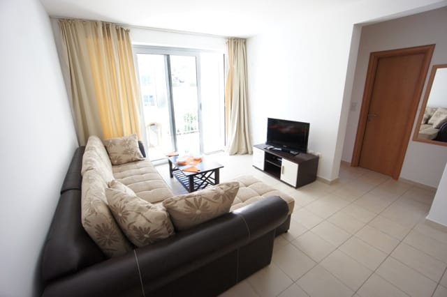 Svetao dnevni boravak sa ugaonom garniturom i izlazom na balkon u stanu u Petrovcu, Crna Gora.