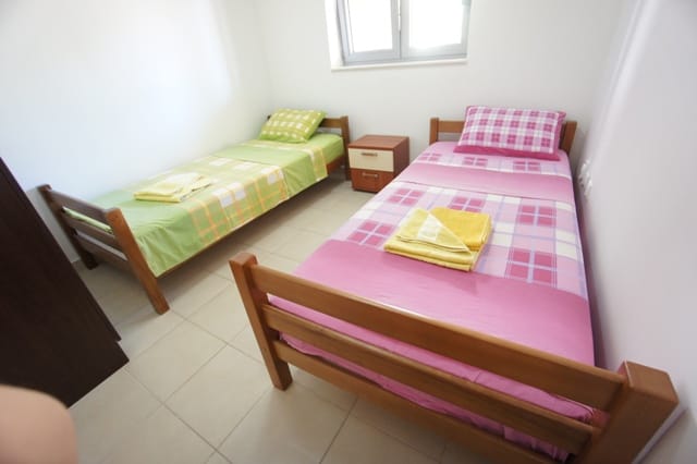 Spavaća soba sa dva jednokrevetna kreveta u stanu, Petrovac, Crna Gora: svetla završna obrada i drveni nameštaj.