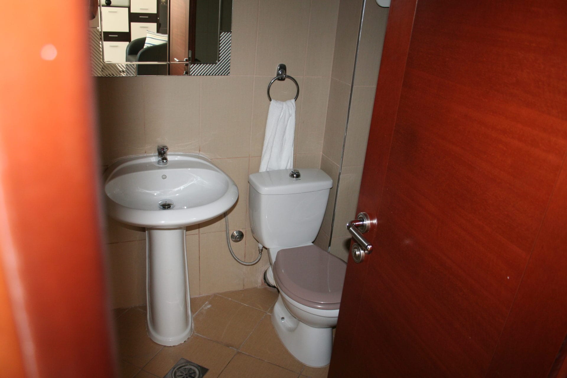 Kupatilo u stanu u Bečićima, Crna Gora: bela sanitarija, lavabo na postolju i keramičke pločice na zidovima.