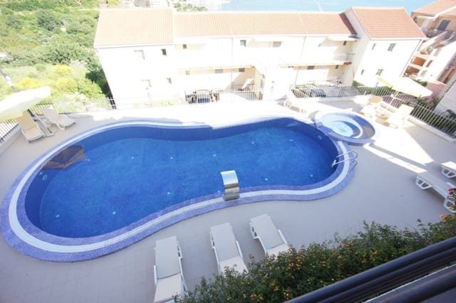 Otvoreni bazen sa đakuzijem i ležaljkama uz stambeni kompleks u Bečićima, Crna Gora, pogled odozgo na hotelski kompleks.