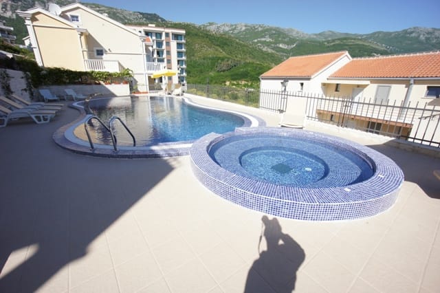 Otvoreni bazen i đakuzi na terasi stambenog kompleksa u Bečićima, Crna Gora, s pogledom na planine i ležaljkama.