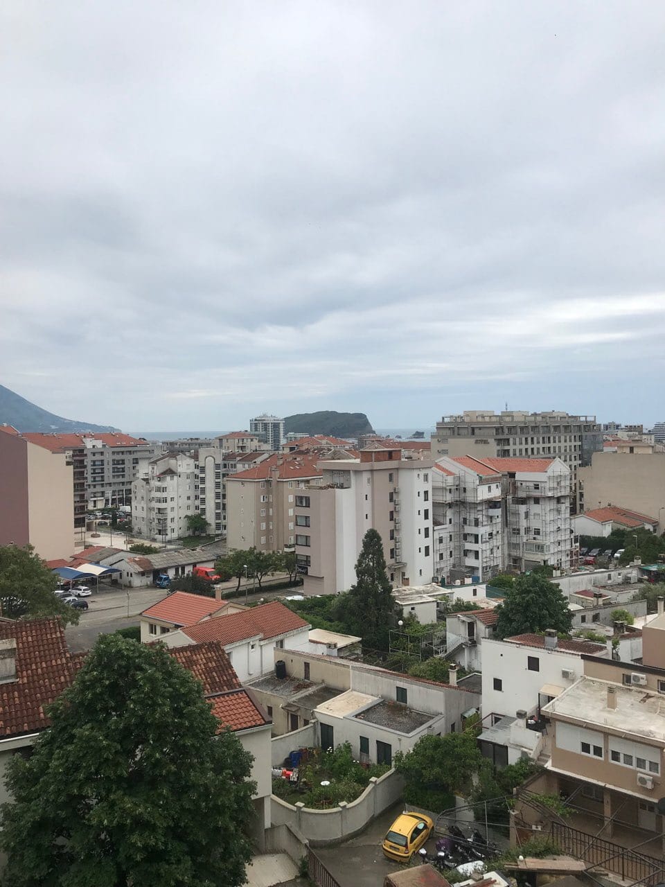 Panoramski pogled na grad Budvu, Crna Gora, sa stambenim zgradama, krovovima od crepa i morskom obalom na horizontu.