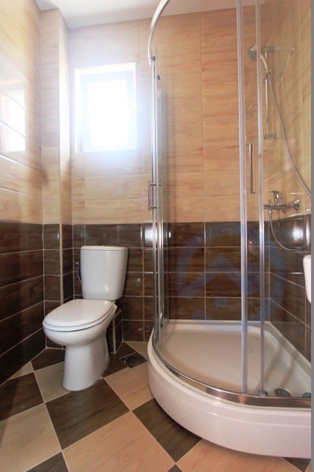 Badezimmer in einer Wohnung in Petrovac, Montenegro: Duschkabine, Sanitäranlagen und Fliesen in Brauntönen.