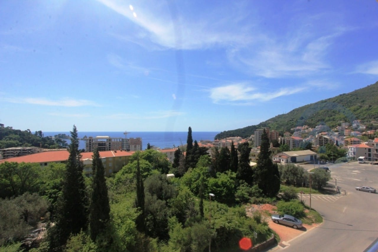 Blick vom Balkon einer Wohnung in Petrovac, Montenegro: Panorama auf das Meer, grüne Hügel und die städtische Bebauung.