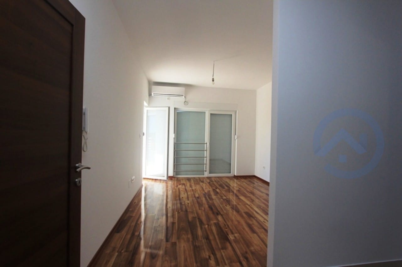 Helles Wohnzimmer mit Parkettboden und Zugang zum Balkon in einer Wohnung in Petrovac, Montenegro.