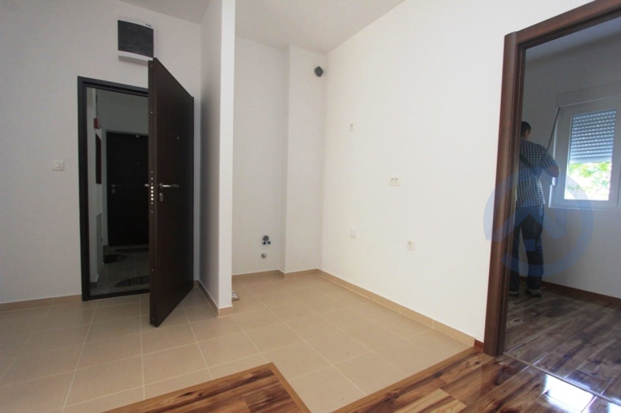 Helle Diele in einer Wohnung in Petrovac, Montenegro: weiße Wände, Fliesenboden und dunkle Innentüren.