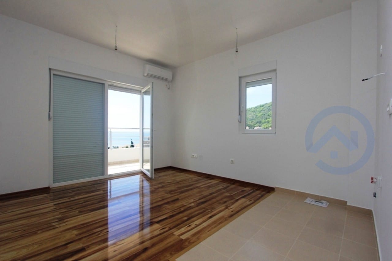 Helles Wohnzimmer in einer Wohnung in Petrovac, Montenegro: Parkettboden, Zugang zur Terrasse mit Blick auf das Meer und die Berge.