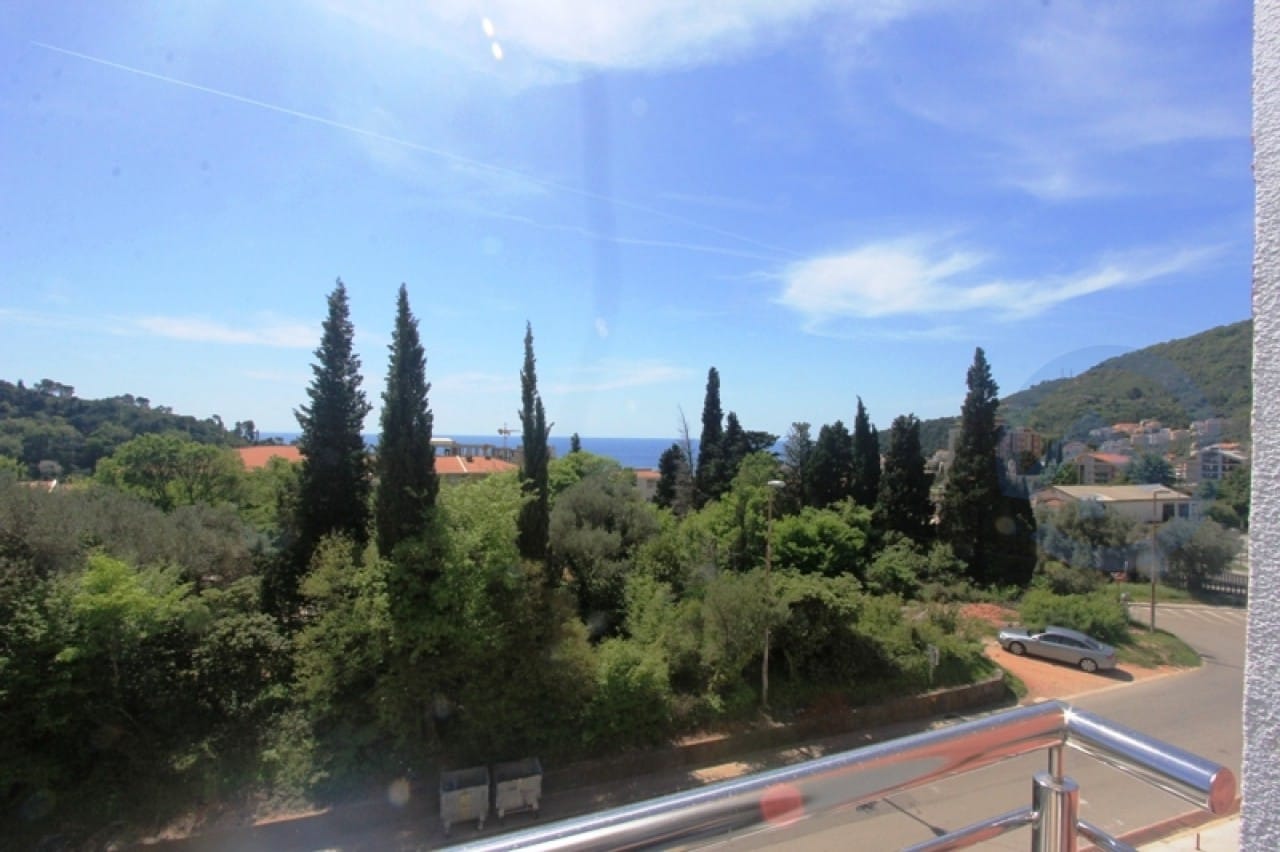 Blick vom Balkon der Wohnung in Petrovac, Montenegro: grüner Park, Zypressen, Meereshorizont und Straße unten.