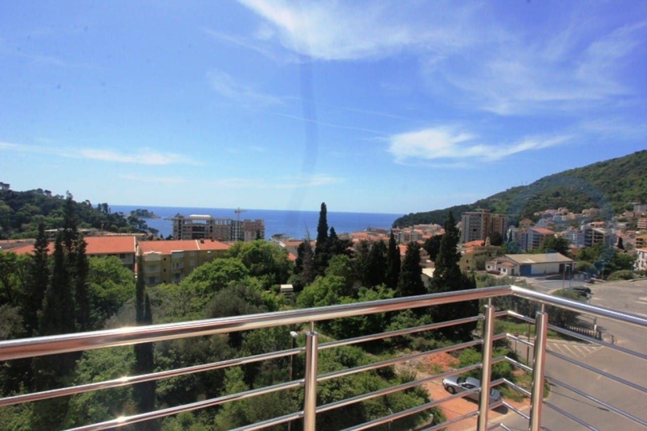 Blick vom Balkon einer Wohnung in Petrovac, Montenegro: Panorama von Meer, Bergen und Stadt mit Metallgeländer.