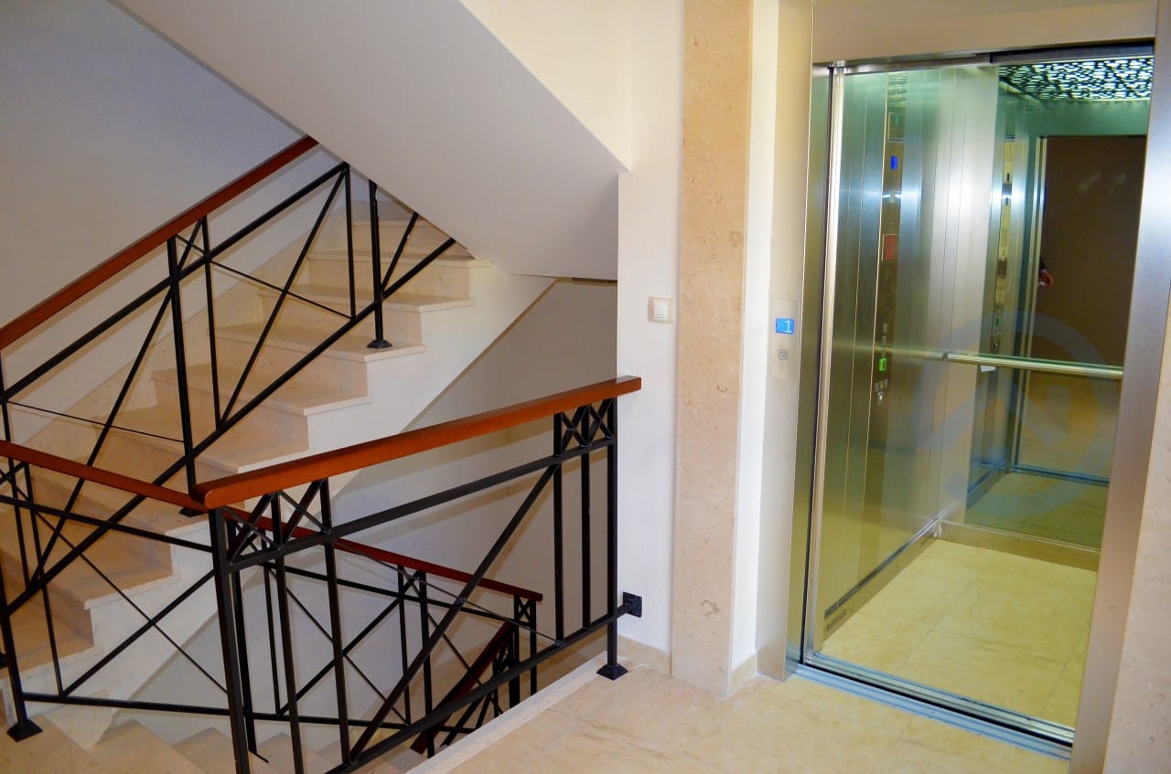 Moderan lift i stepenište sa kovanim ogradama u stambenom kompleksu u gradu Petrovac, Crna Gora.