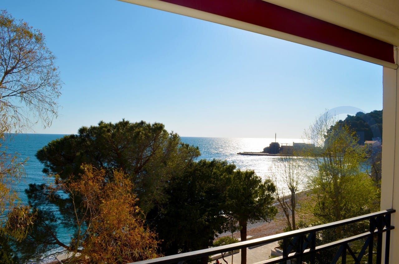 Pogled sa balkona stana u Petrovcu, Crna Gora: panorama Jadranskog mora, plaže i borove šume na obali.