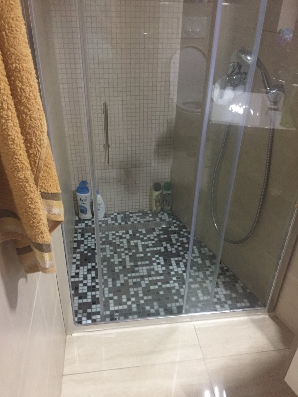 Salle de bain dans un appartement à Petrovac, Monténégro : cabine de douche avec mosaïque et portes en verre.