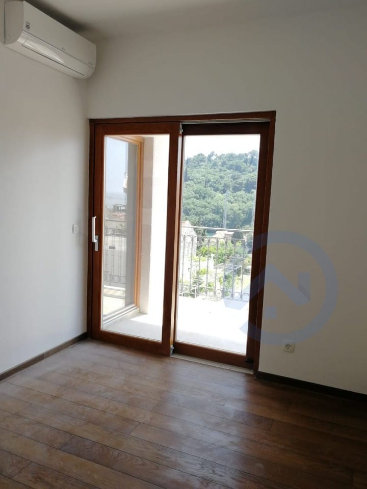 Salon lumineux avec parquet, climatisation et accès à la terrasse avec vue sur les montagnes, appartement à Petrovac, Monténégro.