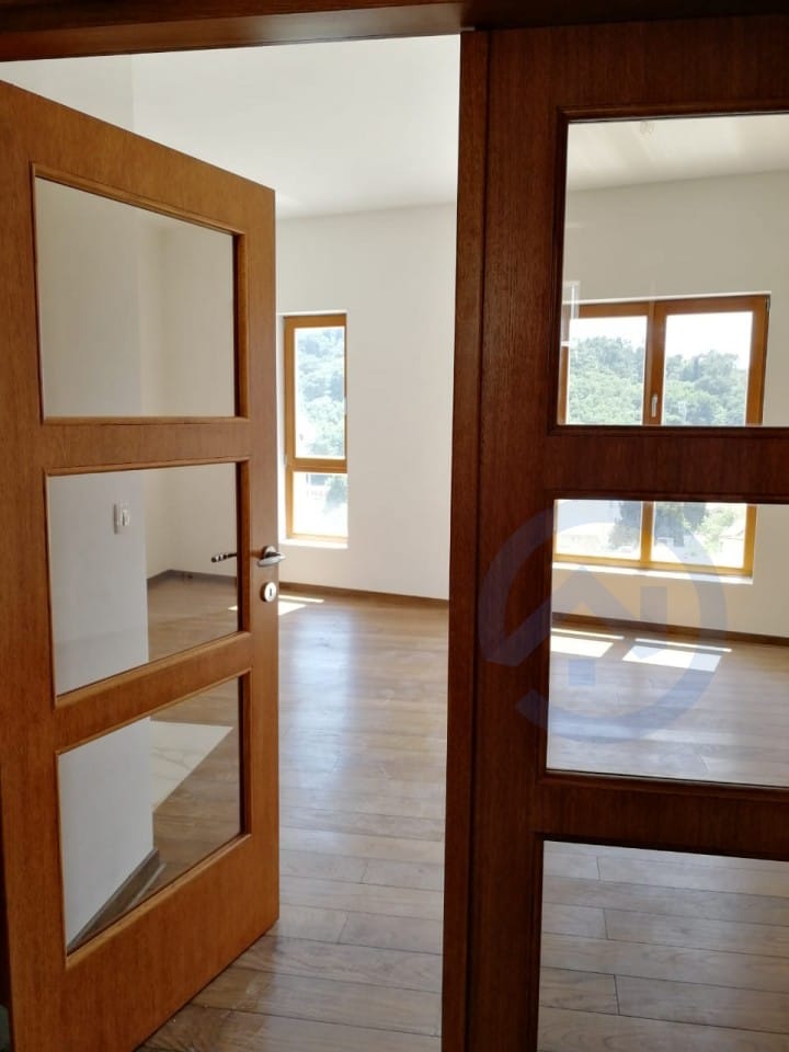 Salon lumineux avec portes en bois et parquet dans un appartement sur la Riviera de Budva, à Petrovac, au Monténégro.