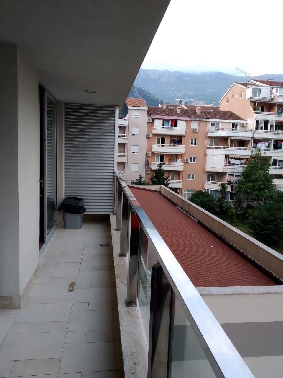 Prostran balkon stana u Budvi, Crna Gora, sa panoramskim pogledom na planine i gradsku izgradnju.