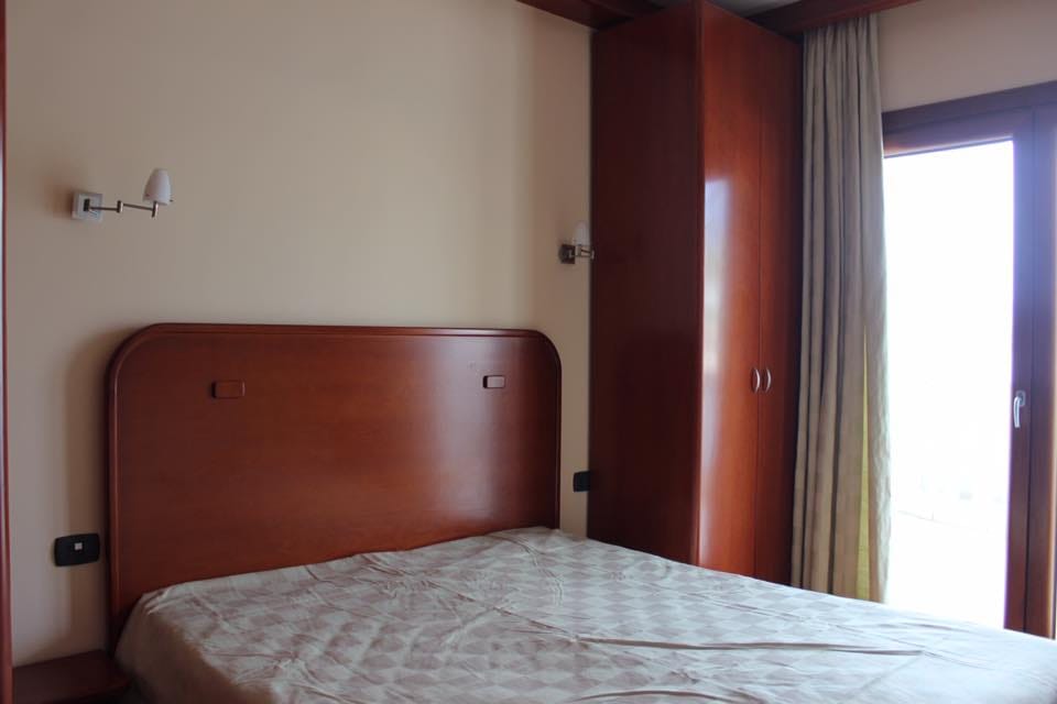Spavaća soba sa bračnim krevetom i ugradnim ormarom u stanu u Rafailovićima, Crna Gora, izlaz na balkon.